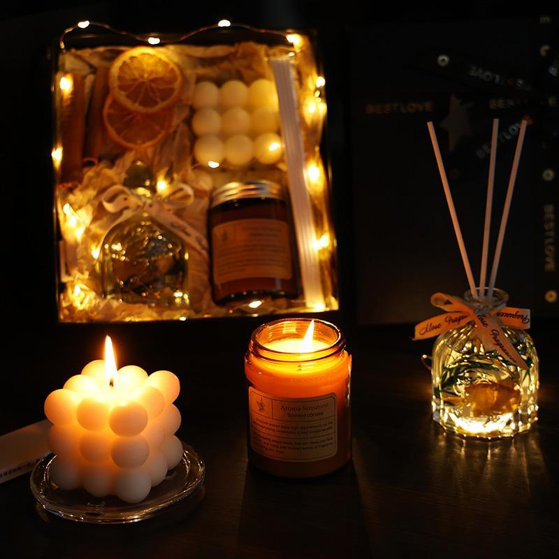 “Luxury candle gift set with diffuser, soy candle and bubble candle on dark surface with warm fairy lights”