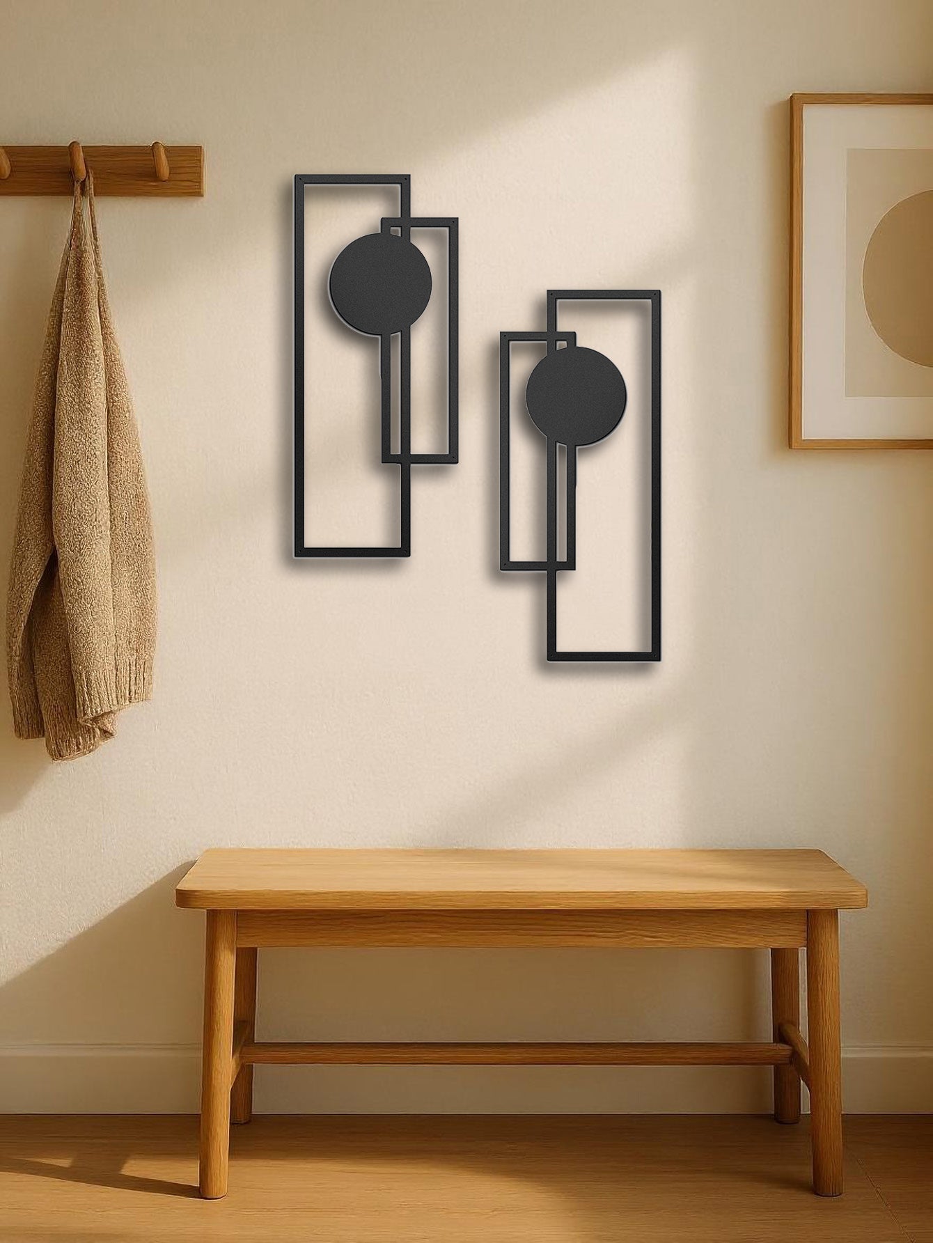 minimalist black geometric metal wall art above wooden bench in neutral entryway
