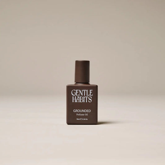 Brown bottle labeled “Grounded” perfume oil on soft beige background