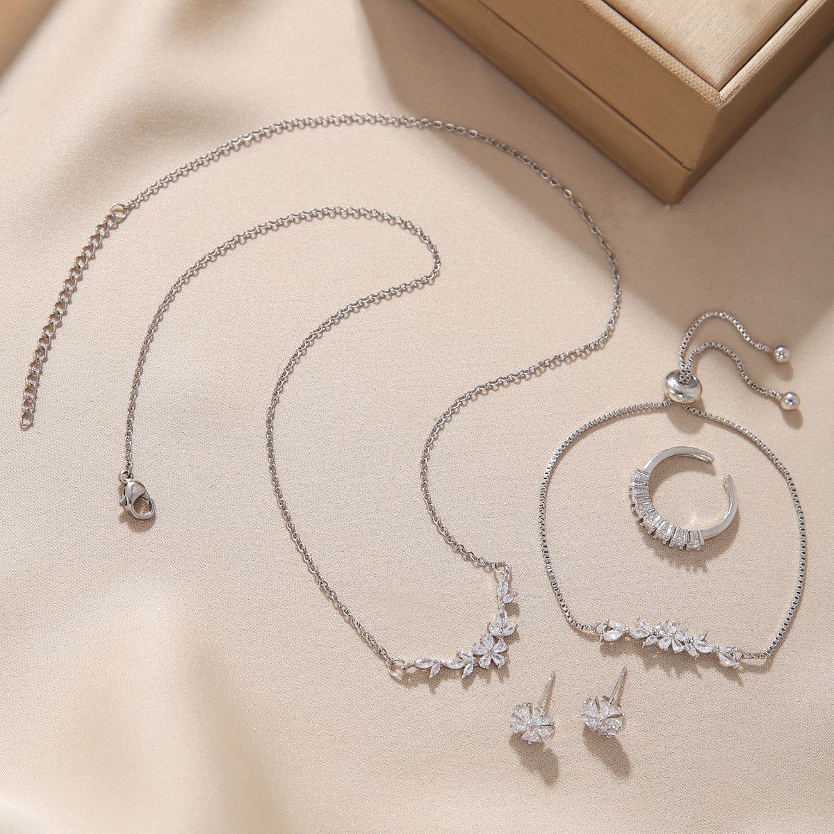 “Complete silver zircon jewelry set arranged neatly with matching necklace, bracelet, ring and earrings”