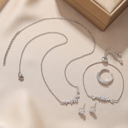 “Complete silver zircon jewelry set arranged neatly with matching necklace, bracelet, ring and earrings”